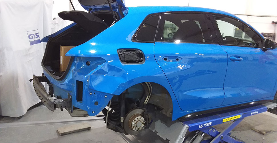 Blue vehicle undergoing professional accident repair in the workshop